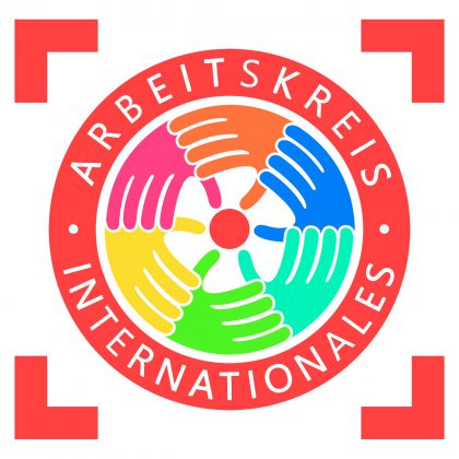 Auf diesem Bild ist das Logo des Arbeitskreises für Internationales abgebildet. Das Logo ist rund und zeigt 6 Hände in den Farben grün, türkis, blau, orange, pink und gelb, deren Daumen alle auf einen roten Kreis in der Mitte zeigen. In weißer Schrift auf rotem Grund steht: Arbeitskreis Internationales. 